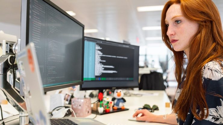 Woman Coding in Office on two Monitors